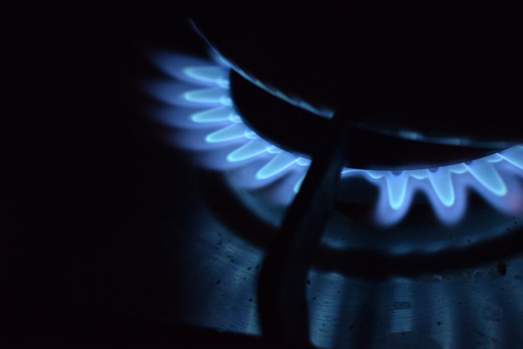 A family using a kitchen with a gas stove and a propane tank visible outside a window.