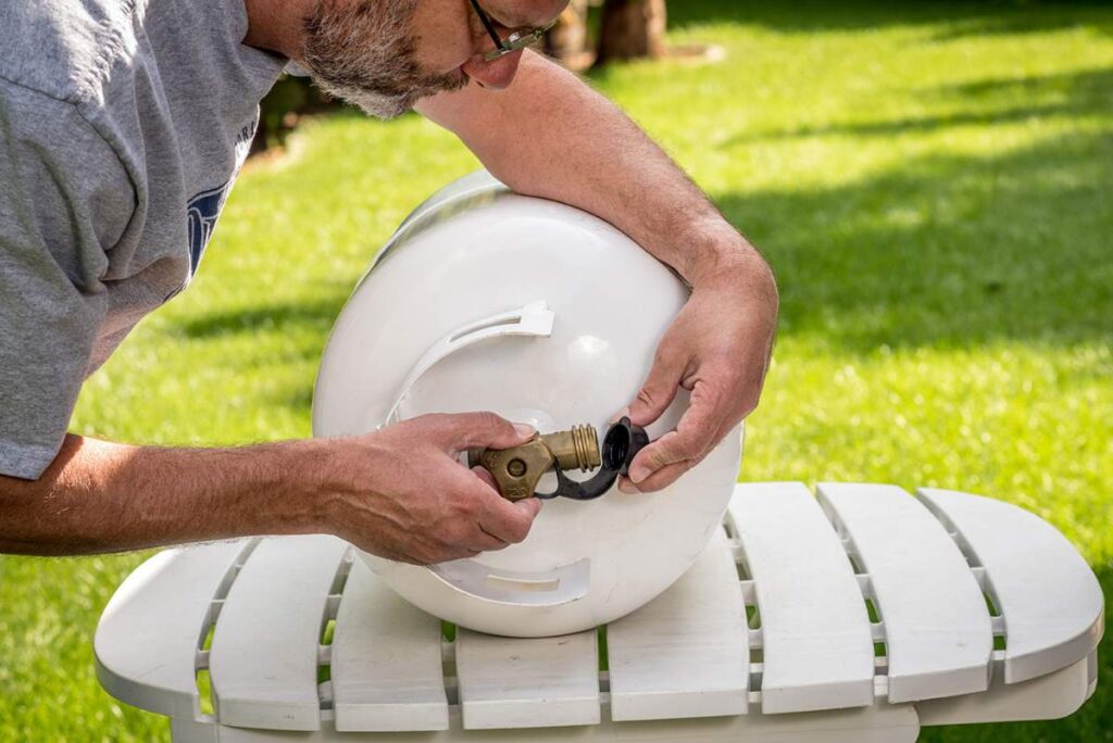 Outdoor propane tank with visible vapor space, pressure valve, and sunlight warming the metal surface.