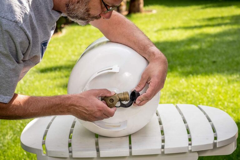 Outdoor propane tank with visible vapor space, pressure valve, and sunlight warming the metal surface.